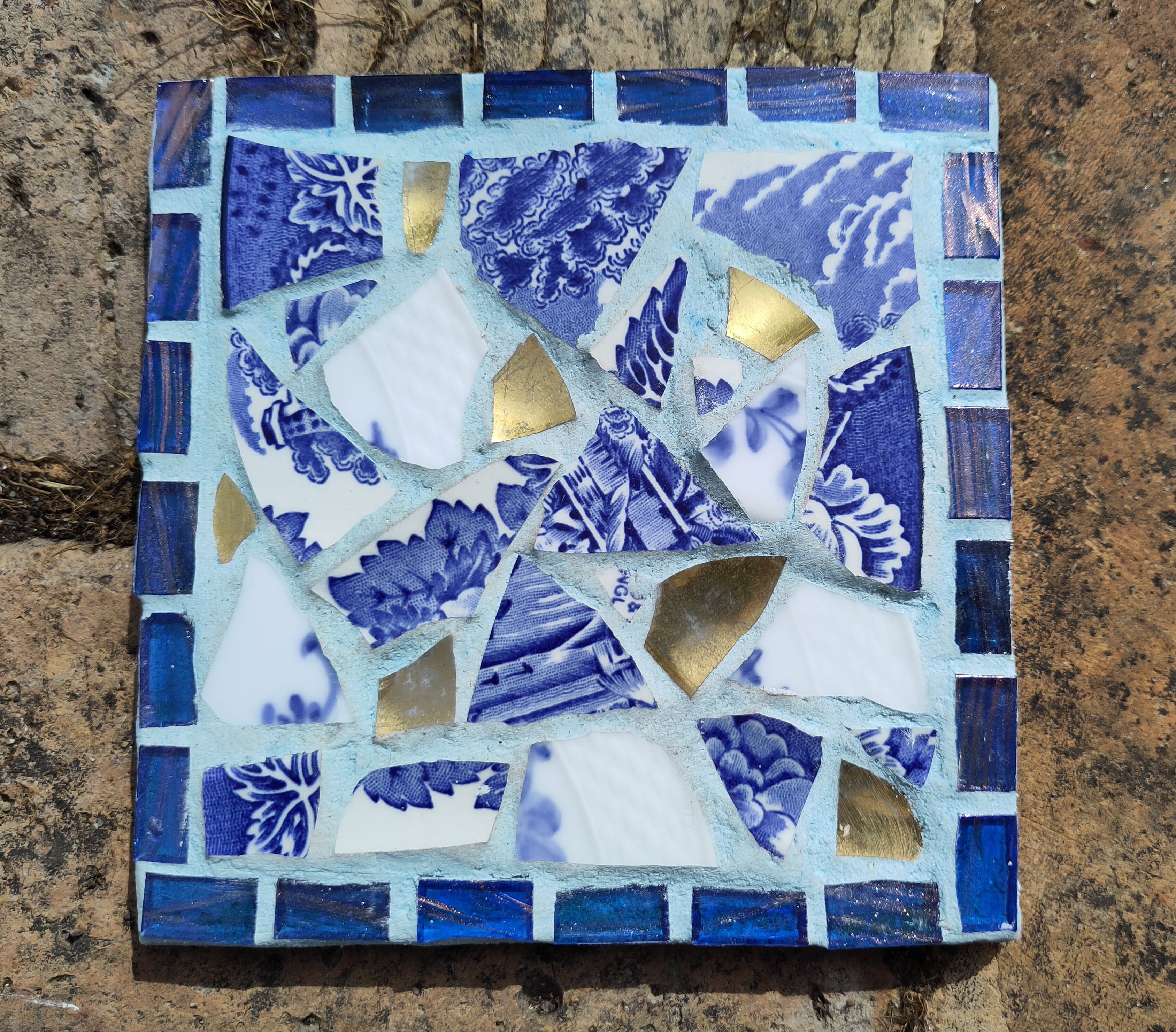 Mosaikbordskåner med blåmønstrede skår , guldskår og lys blå fuge. Lotte Rosenkilde.