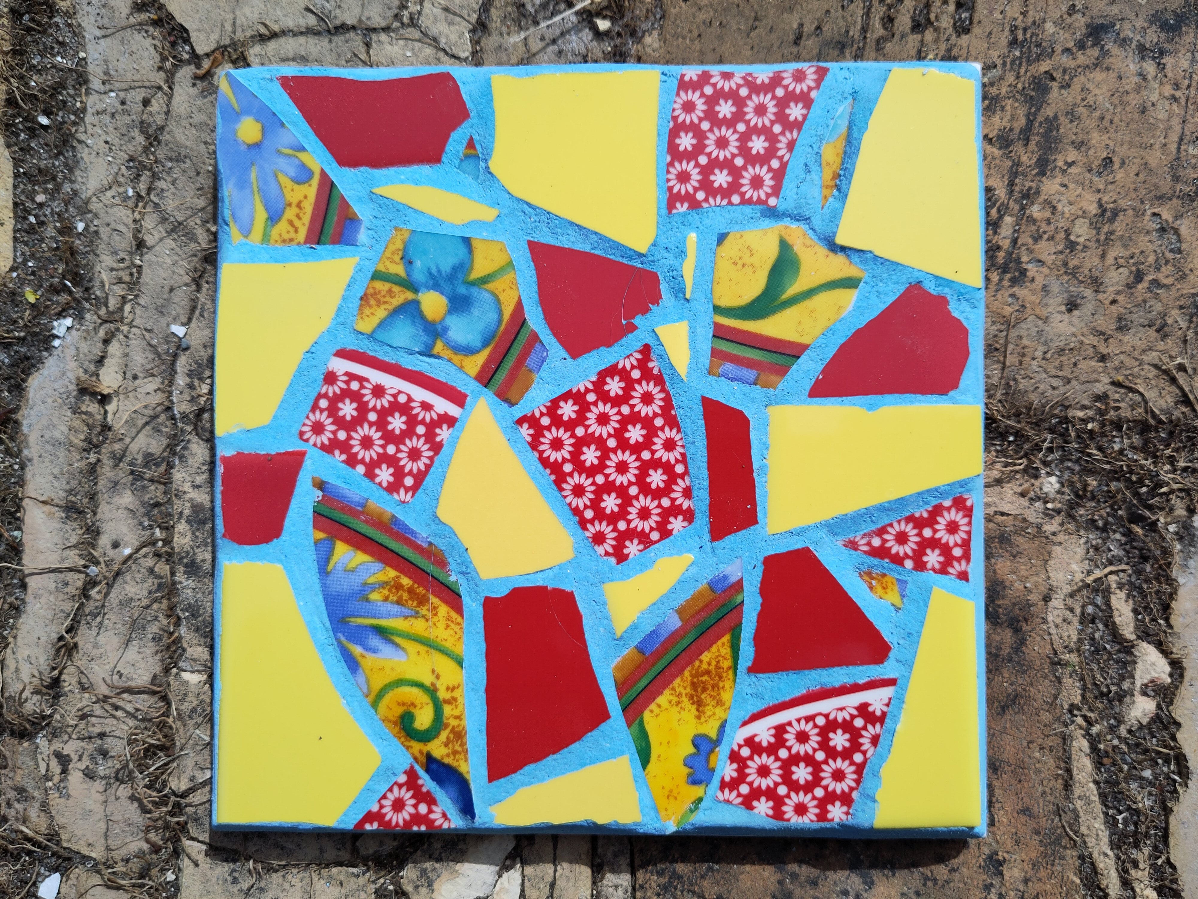 Mosaikbordskåner med gule, røde og blomstrede skår. Lotte Rosenkilde.