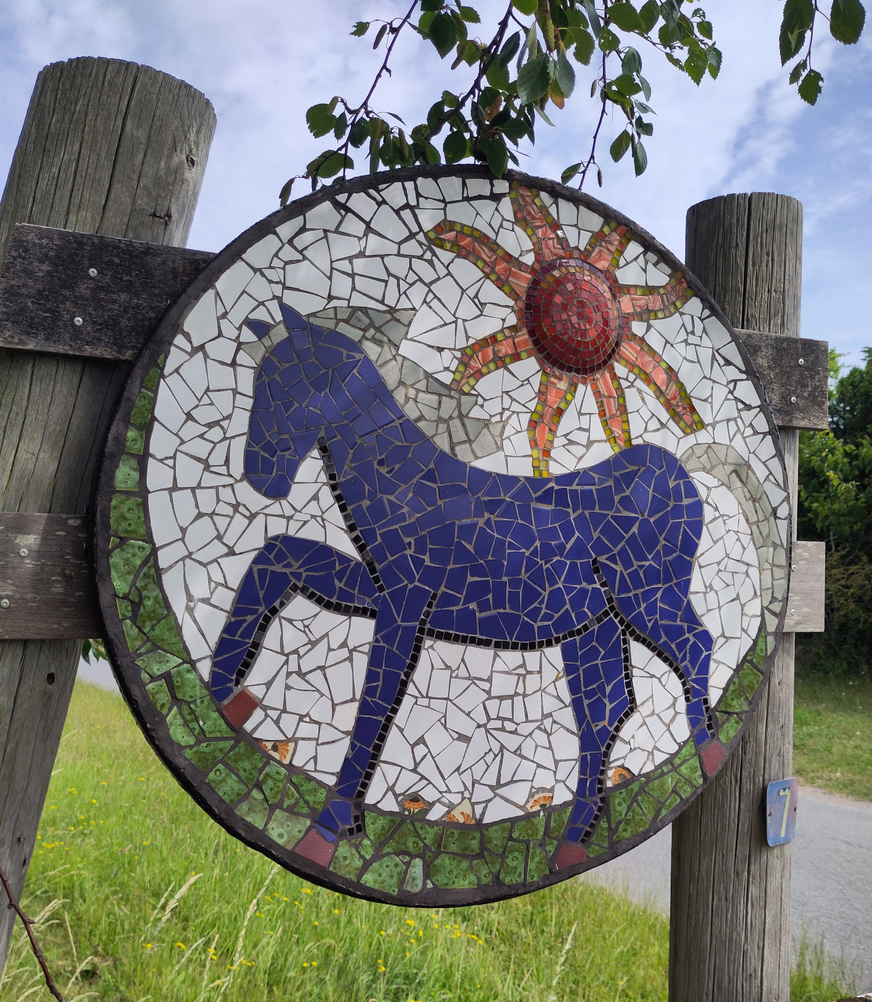 Rund mosaik med blå hest og sol af Lotte Rosenkilde.