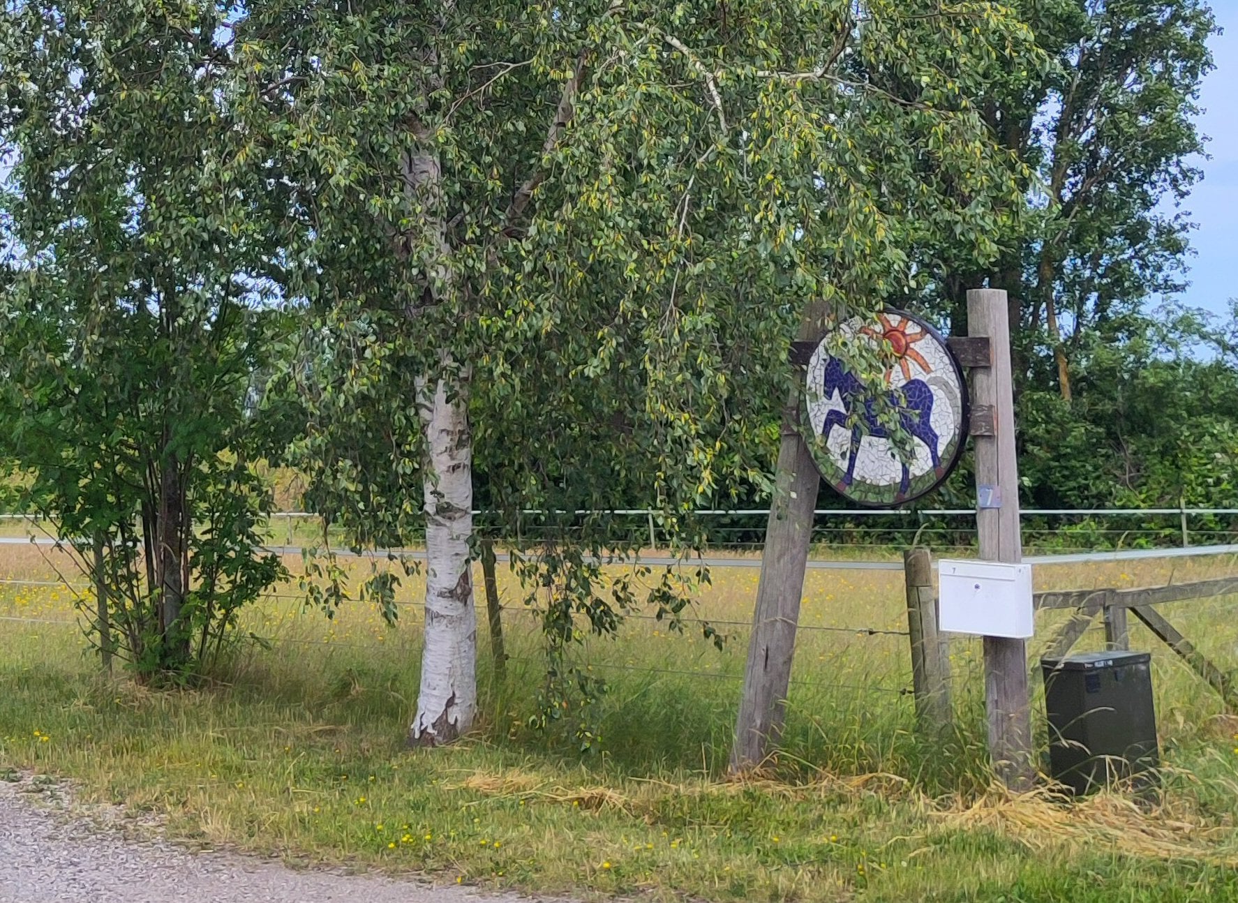 Rund mosaik med blå hest og sol af Lotte Rosenkilde.